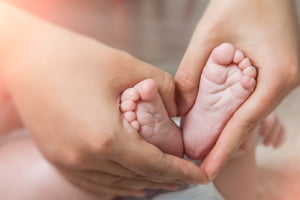 Small newborn baby legs in mothers lovely hand with soft focus on babie's foot